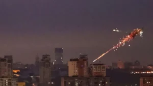 Kyiv skyline at night under Russian aerial bombardment with explosions and anti-aircraft fire, showing widespread attack.